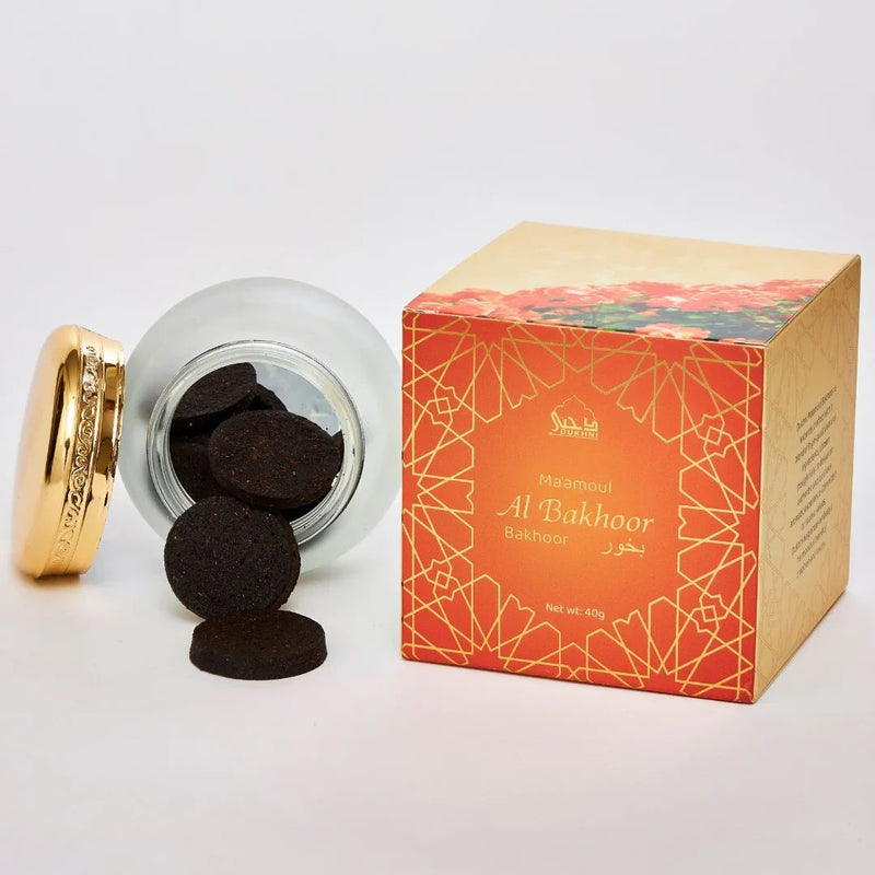 Jar of black incense tablets with an orange box labeled 'Al Bakhoor' on a white background