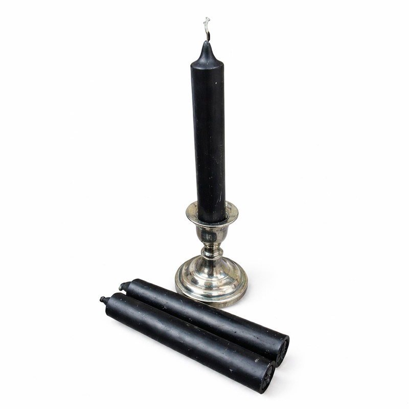 Black candle in a silver holder with two black ritual candles on a white background
