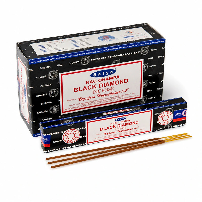 Satya Black Diamond incense stick burning in a wooden holder with smoke rising, grounding ritual setup