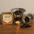 Incense burner with smoking sticks, a box labeled 'Oud Al Khaleej', and a lit candle on a wooden surface.