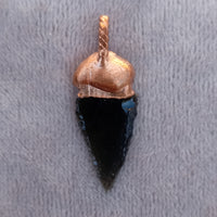 bsidian arrowhead pendant with intricate design, photographed on a Grey velvet cloth.