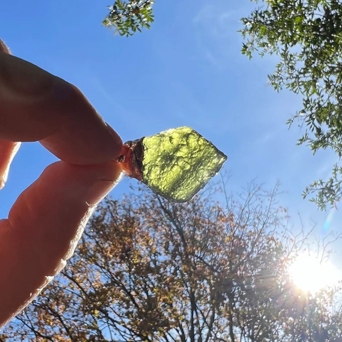 Moldavite Crystal Pendant Held to Sunlight – Showcasing Natural Translucency