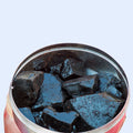 Open container showing solid Shilajit resin pieces with a glossy, dark surface.
