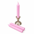 Pink ritual candle and candlesticks on a white background