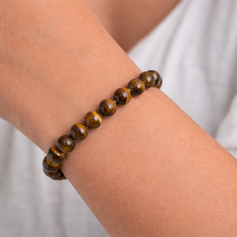 Tigers Eye Crystal beaded bracelet on a wrist with a plain background
