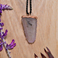 Close-up of spirit quartz pendant hanging against a wooden background with lavender decoration