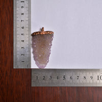 Spirit quartz pendant measured with ruler for scale on white background